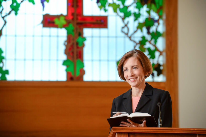 A female chaplain speaks at a lecturn in a chapel