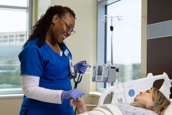 nurse smiles at patient in hospital room
