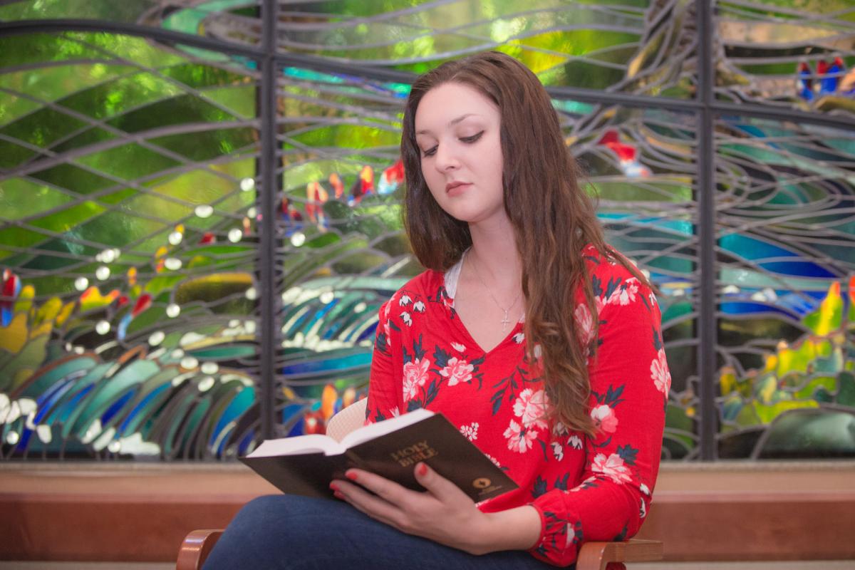 A female student reading a bible in the chapel