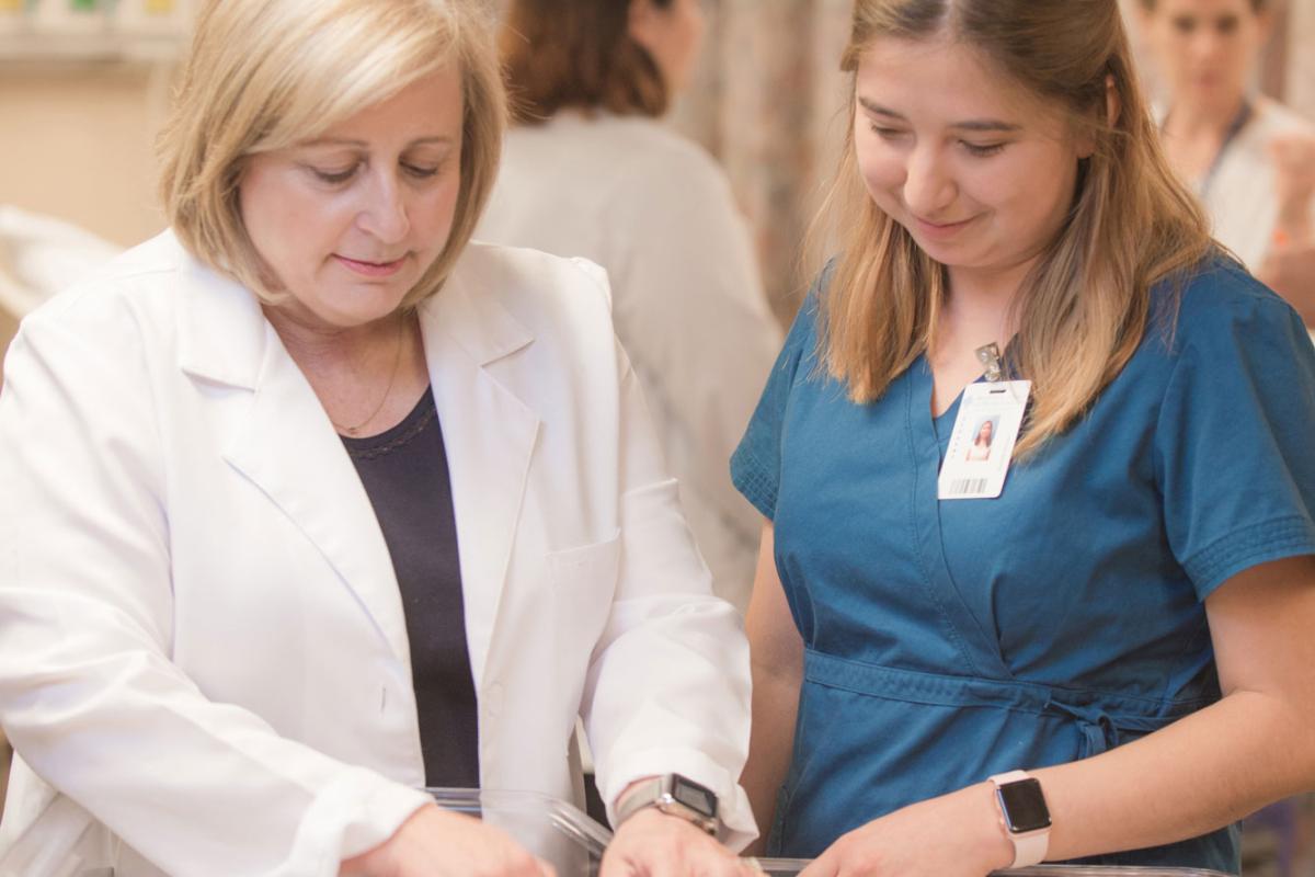 A nursing faculty member teaching skills to a student on an infant simulator