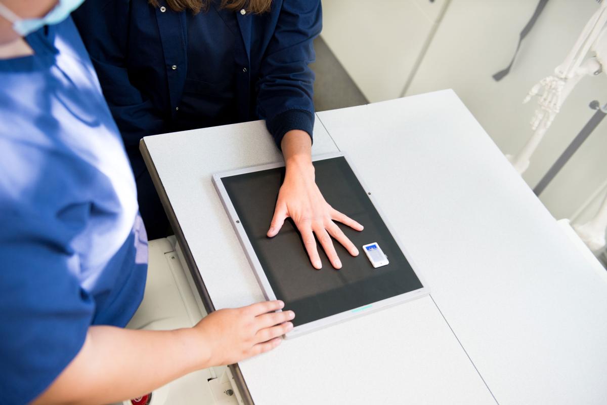 A student positioning another student's hand for x-ray practice