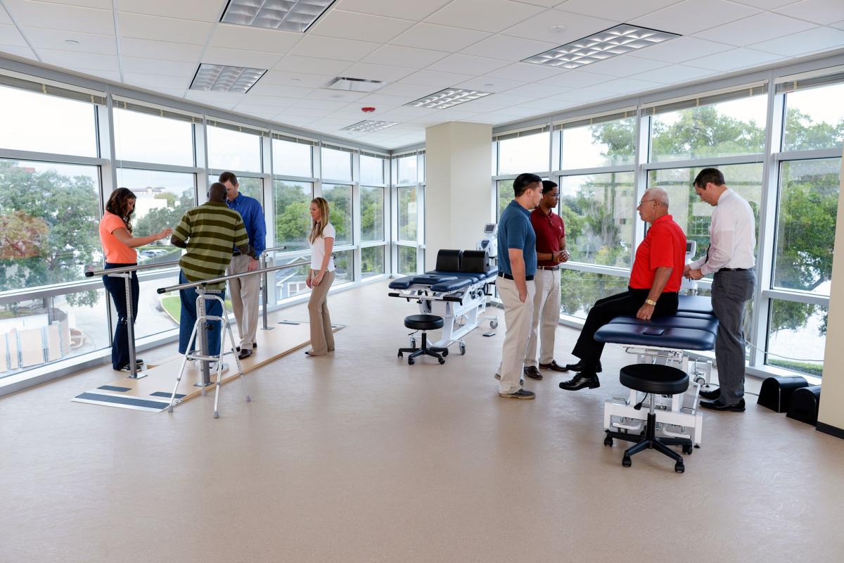 Two faculty members teaching separate groups of students physical therapy skills.