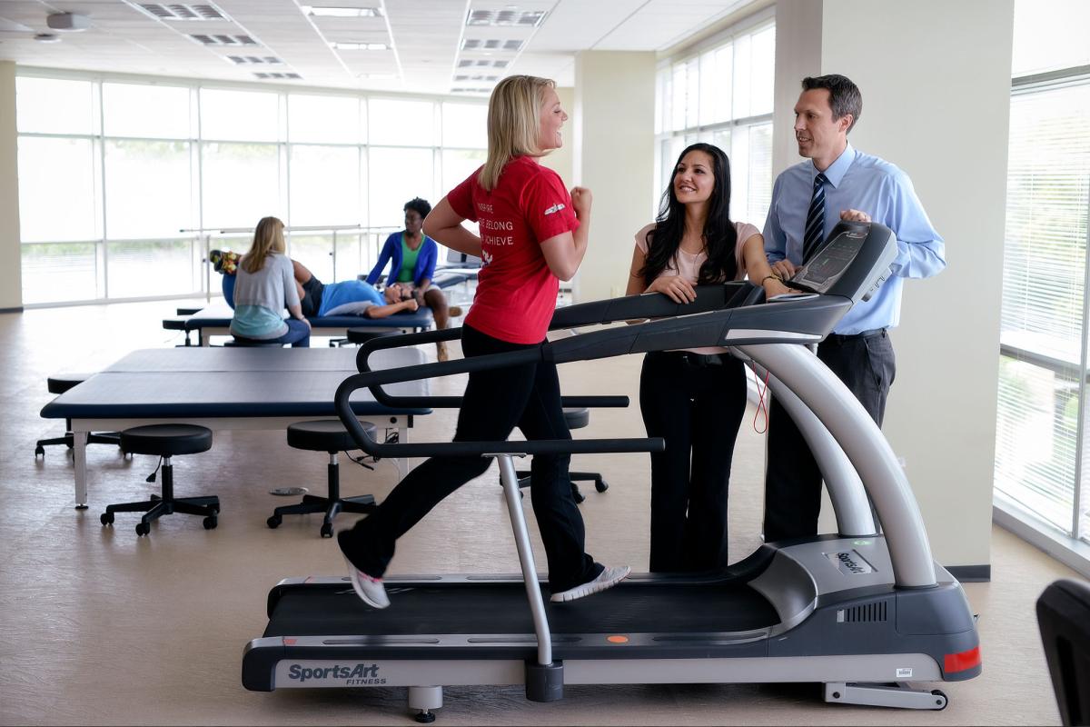 A student runs on a treadmill while a faculty member and another student observe
