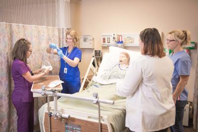 Nursing students practicing in the skills lab under the supervision of a faculty member