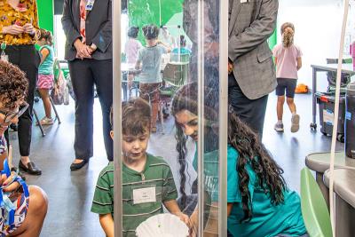 Ruben Martinez smiles and looks at little boy conducting experiment