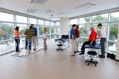 Two faculty members teaching separate groups of students physical therapy skills.