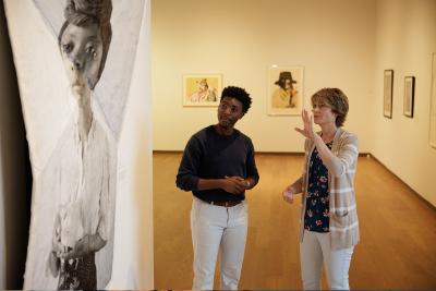 A faculty and student discuss artwork in a museum