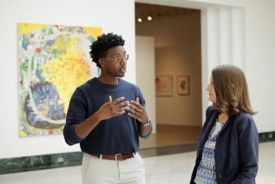 A student converses with a teacher in an art museum