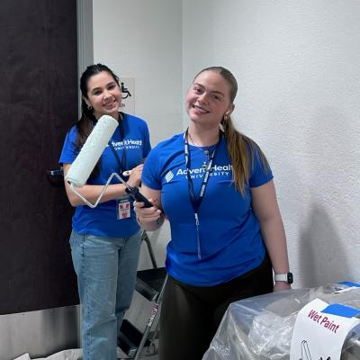 Two students smiling and painting for all AHU service day