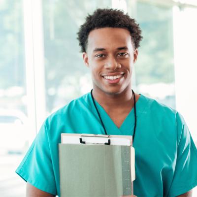 A smiling Male nurse holding a clipboard.