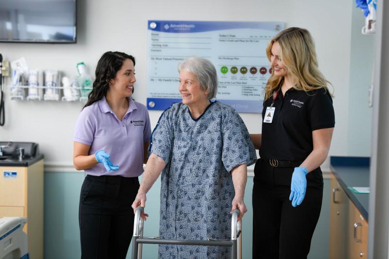 Image of faculty member smiling and helping patient with a student