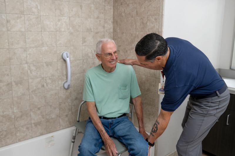 image of male occupational therapy faculty member helping older patient position himself