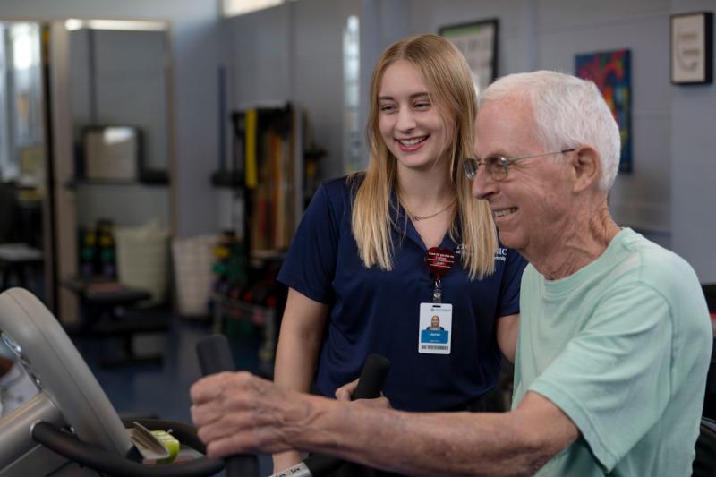 image of occupational therapy assistant student assisting geriatric patient on exercise machine