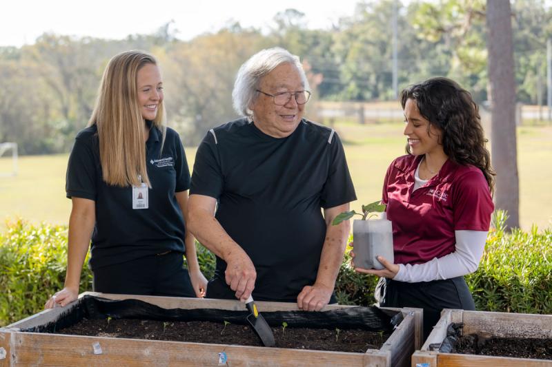 two occupational therapy students helping geriatric patient with gardening