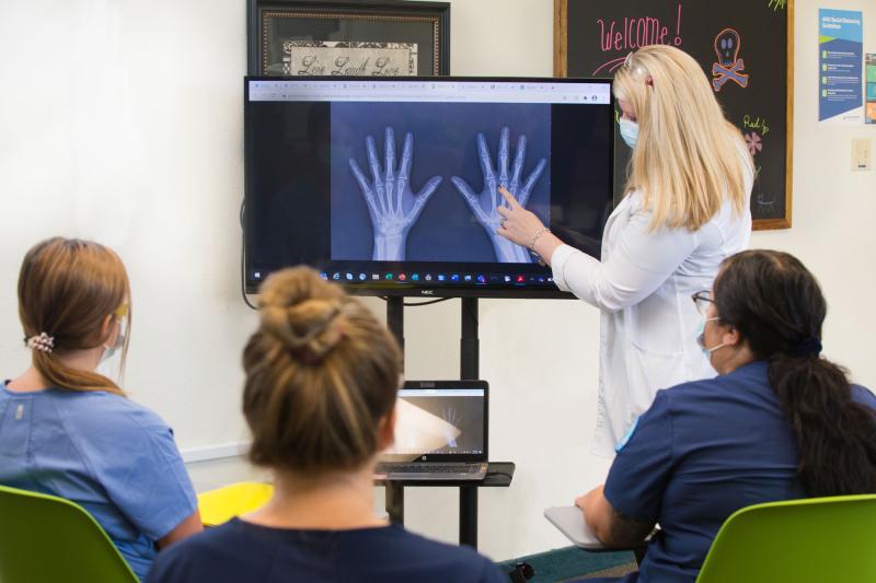 A radiography instructors showing students and x-ray of the hand
