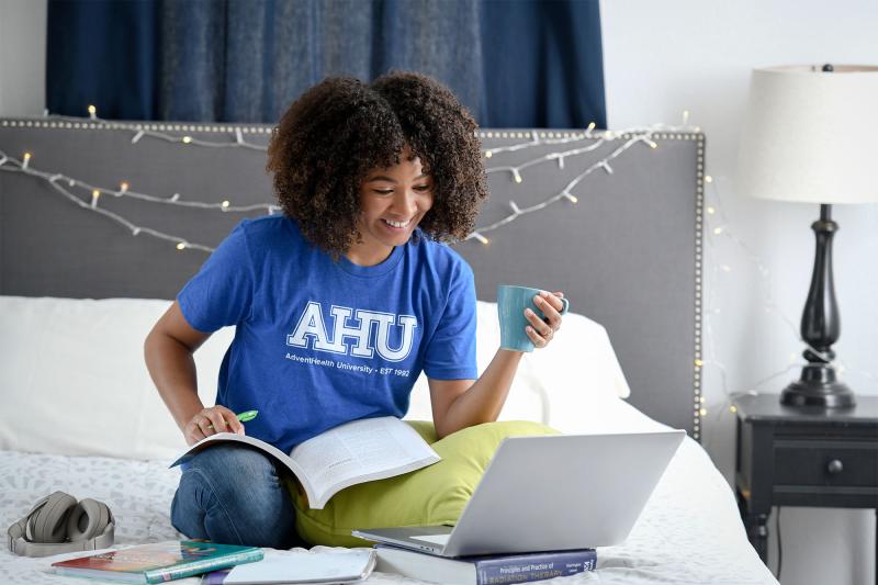 A young female African-American student studying in her dorm room