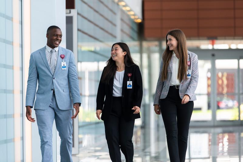 3 students in suits walk down a hallway