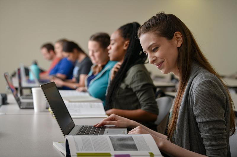 A female student works on her laptop in a classroom