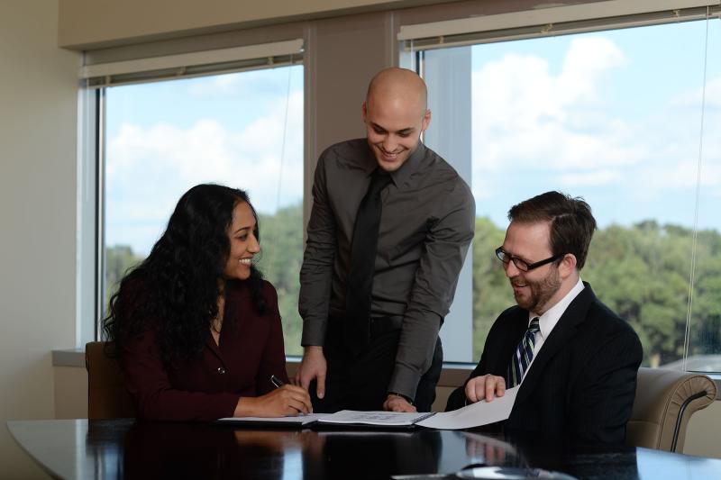 A professor teaches two students at a conference table