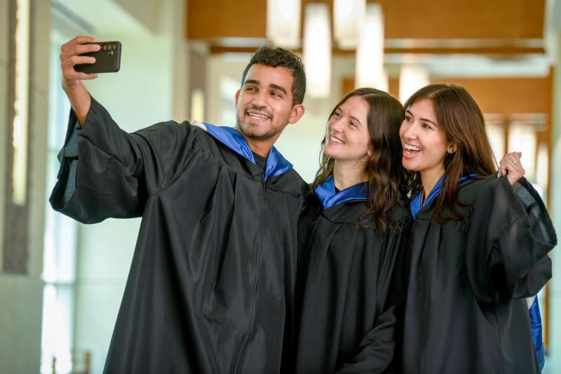 Three graduates smiling in regalia