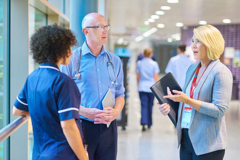 A hospital administrator converses with a doctor and nurse