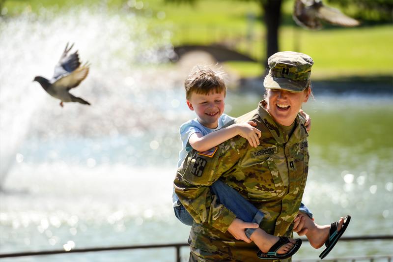 Military mom in uniform sitting with her kids in the park