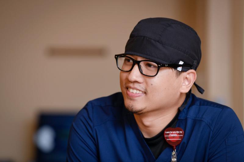 A male nurse in scrubs and a cap