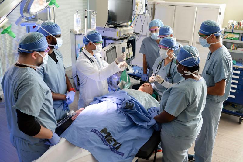 A group of students participating in an operating room simulation under faculty supervision