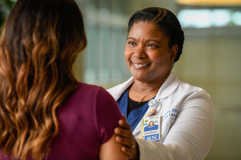 A nurse practitioner puts her hand on a person's shoulder