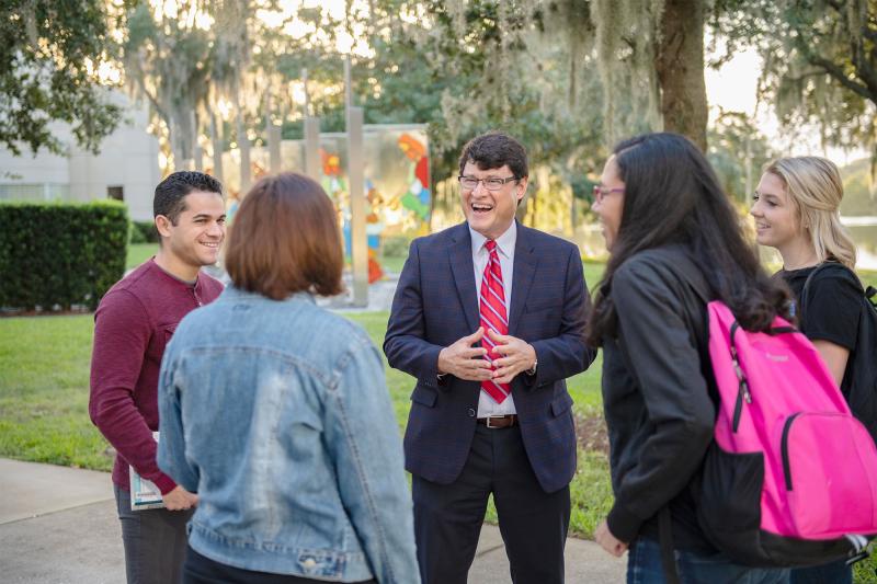 AHU President Hernandez outdoors conversing with students