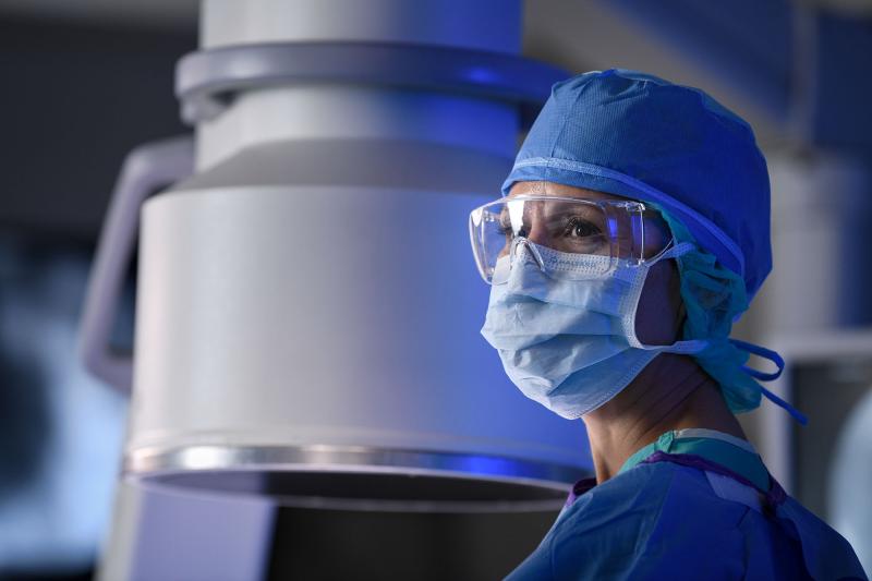 A healthcare worker in a mask and scrubs in an operating room