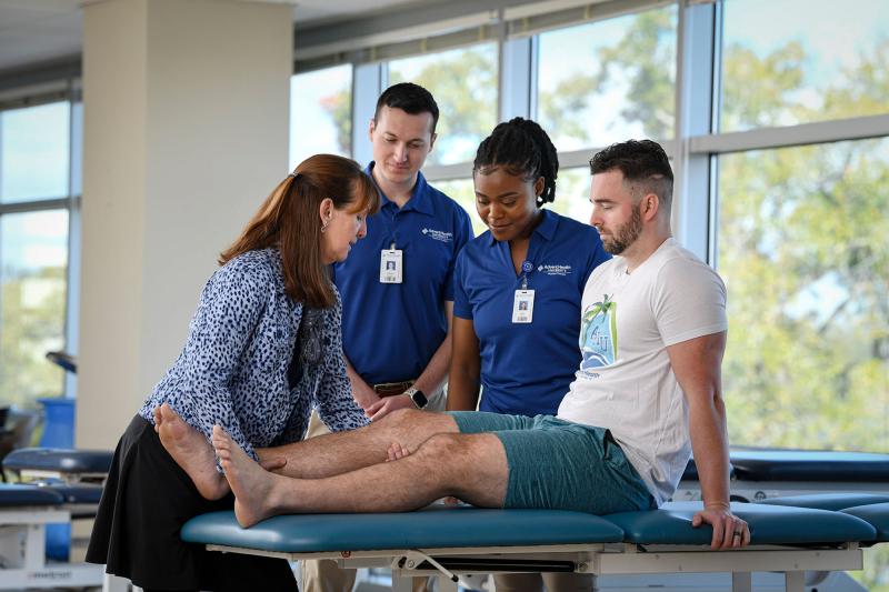 Physical therapy faculty and students practicing on patient table