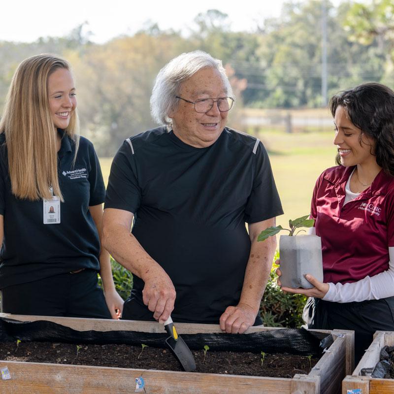 two occupational therapy students helping geriatric patient with gardening