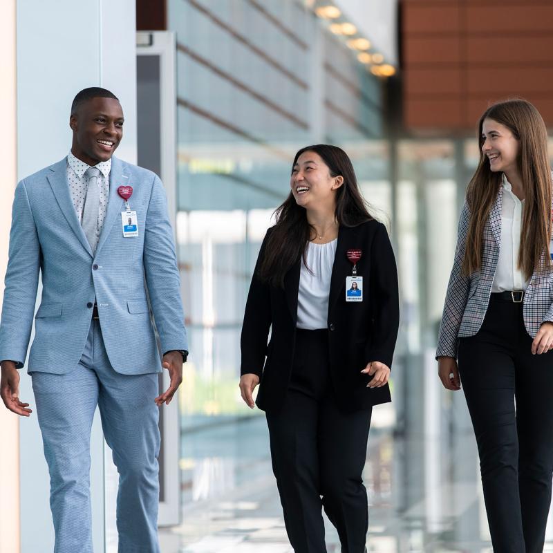 3 students in suits walk down a hallway