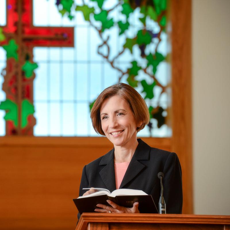 A female chaplain speaks at a lecturn in a chapel