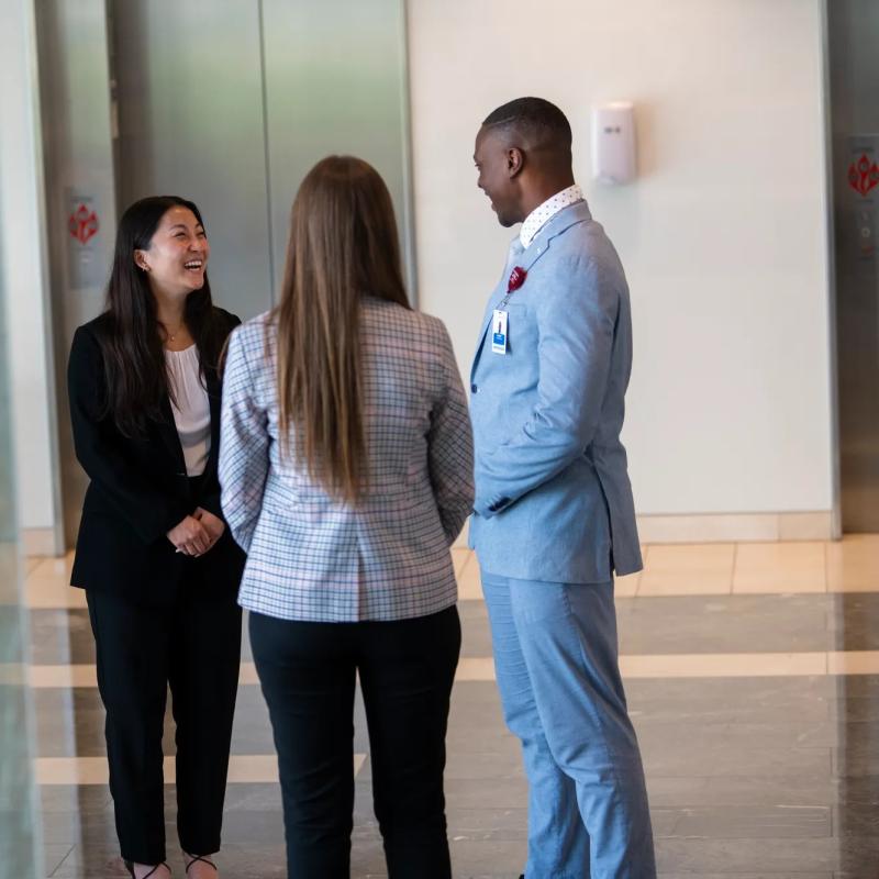three adventhealth employees smiling and talking in hallway of hospital