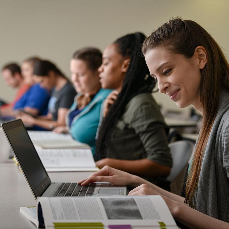 A female student works on her laptop in a classroom