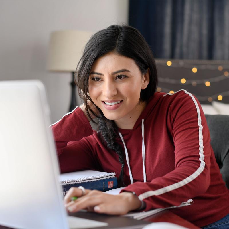 A female student working on her computer in her dorm room.