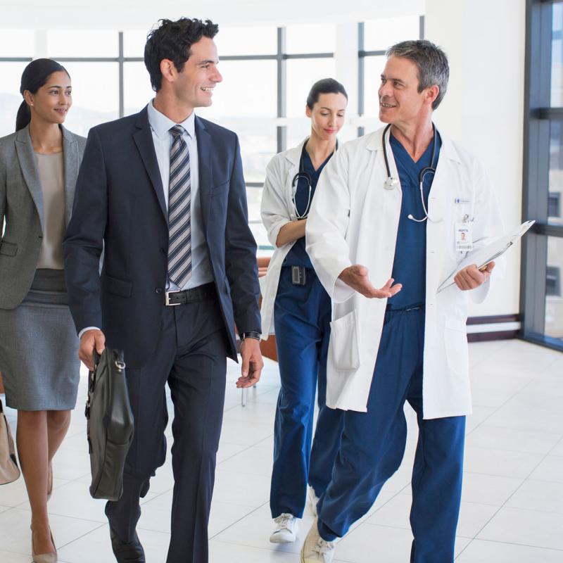 A doctor conversing with an administration team while walking