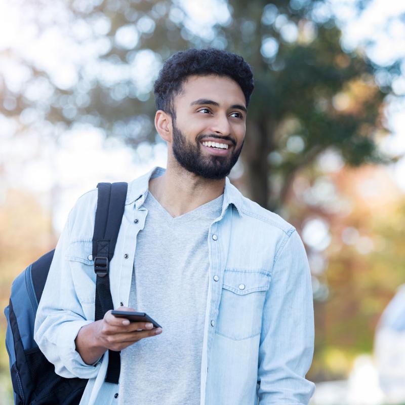 A middle-eastern male student walking outside on campus