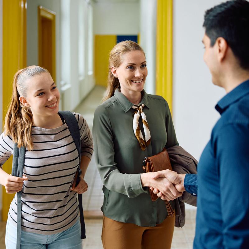 A new female student and her mother shake hands with a university team member
