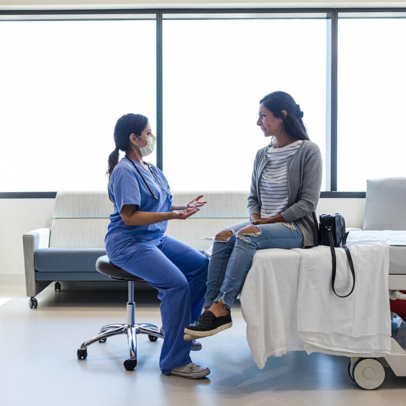 A nurse speaks with a patient in an exam room