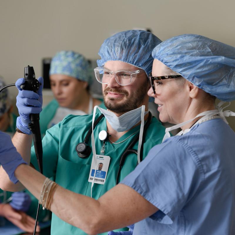 A male nurse anesthesia student using equipment with the help of a faculty member