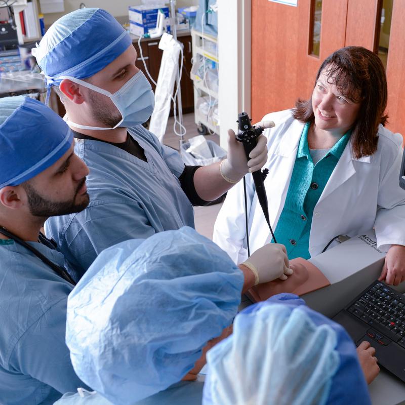 A group of nurse anesthesia students practice using an endoscope under faculty supervision