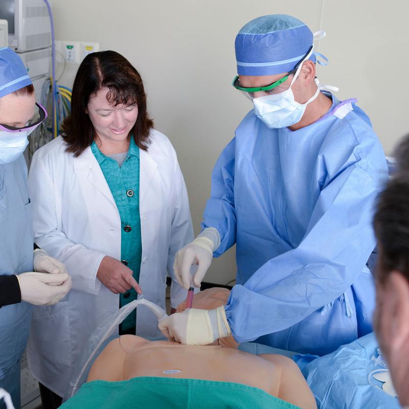 A nurse anesthesia student practices ultrasound-guided injection while a faculty member supervises and other students observe.