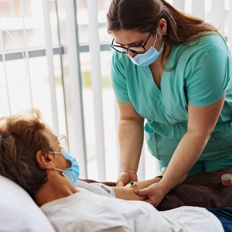A registered nurse places an IV drip on a patient