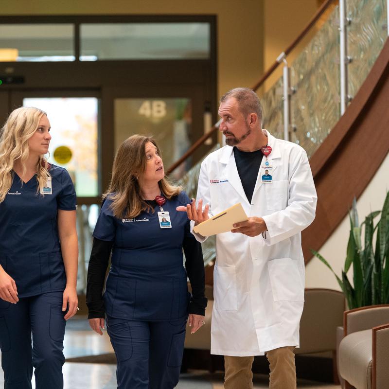 A nurse leader walks and converses with nurse team members