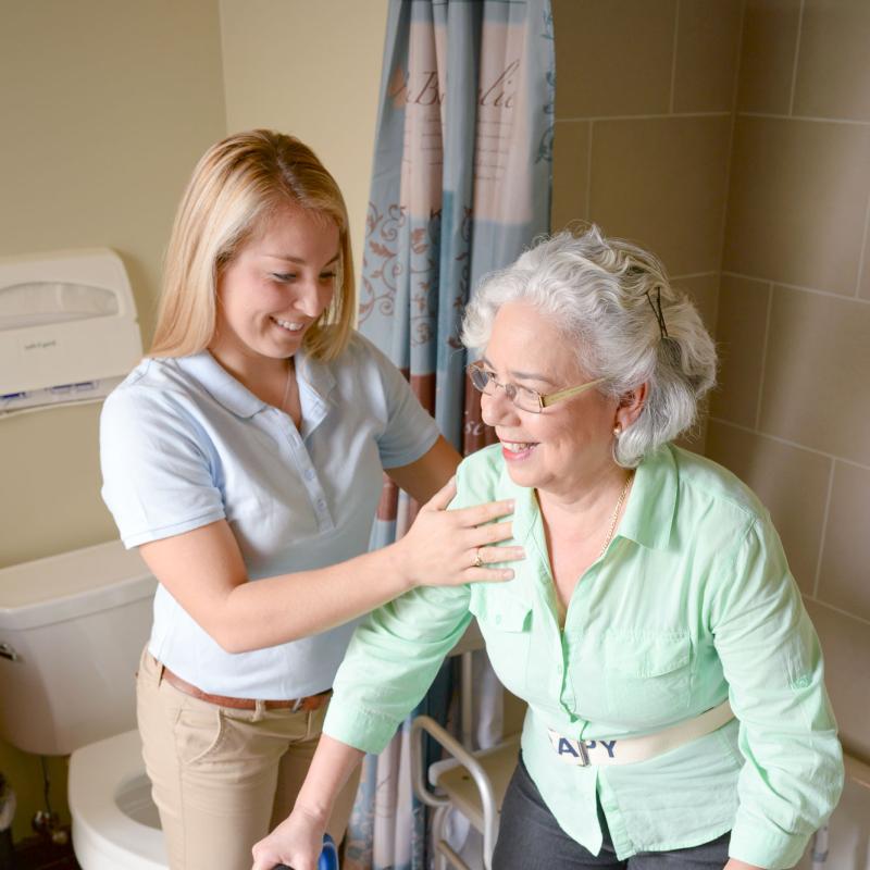 A female occupational therapy student assisting an elderly patient in the bathroom
