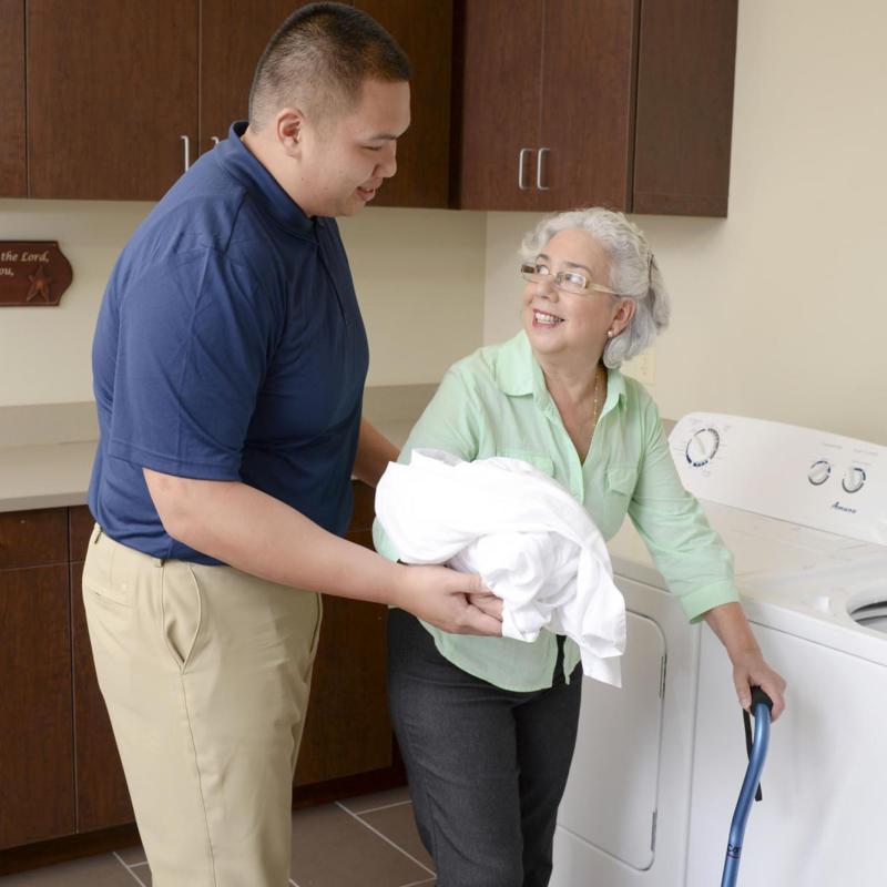An occupational therapy student aiding an elderly patient in doing laundry.
