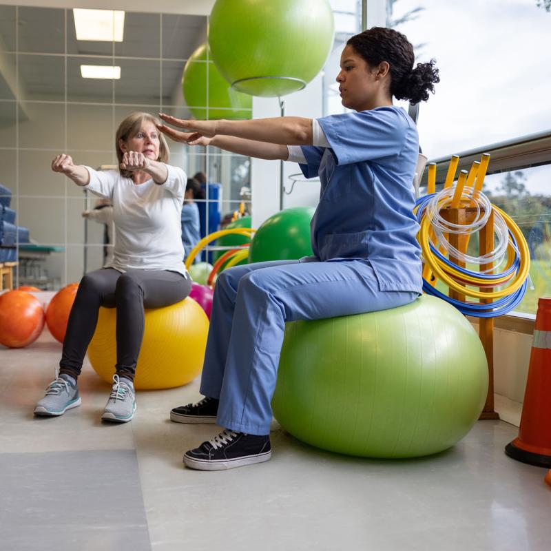A female occupational therapist works with a patient using swiss exercise balls